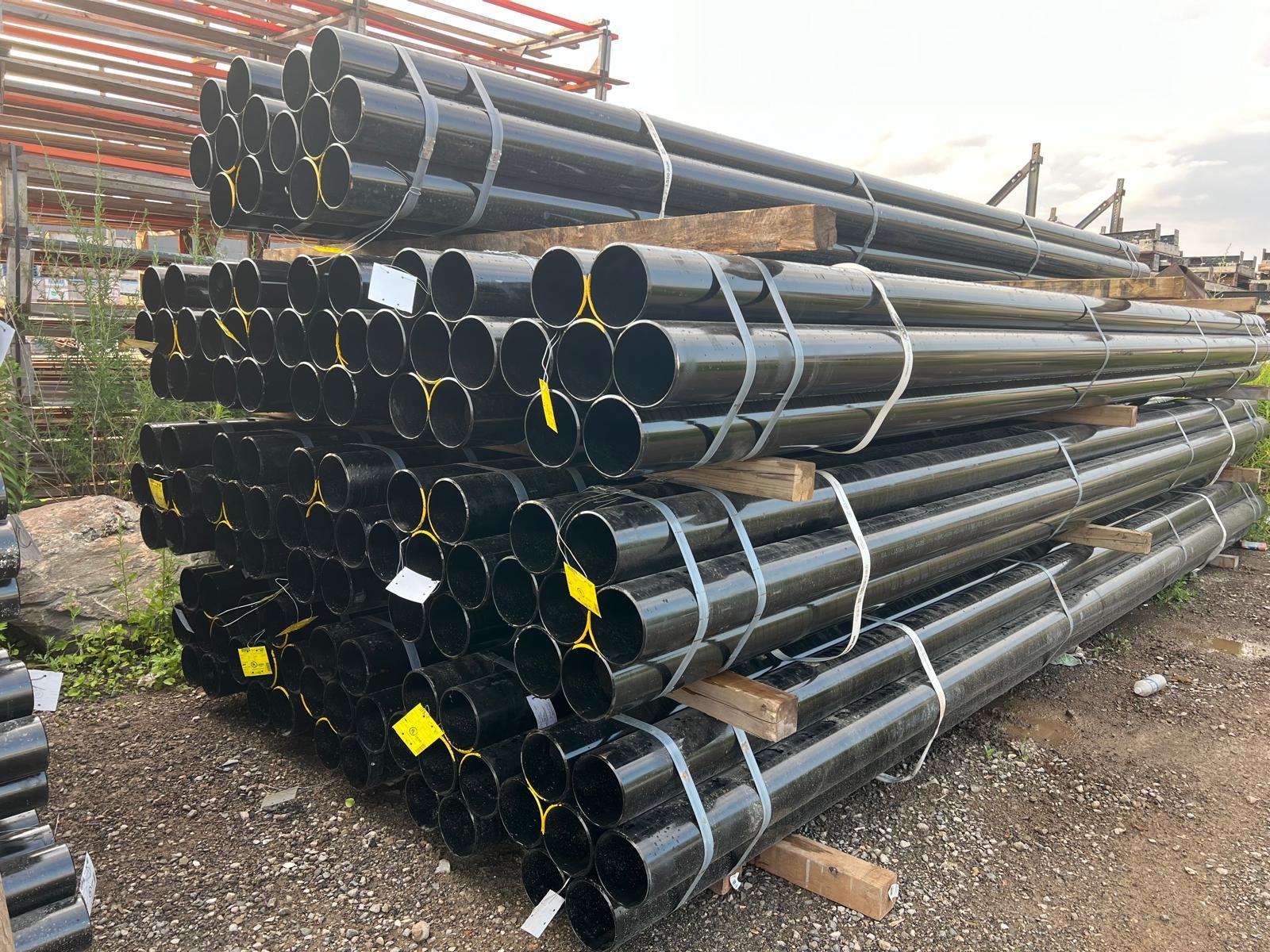 Powder-coated steel pipes stacked and bundled at the yard